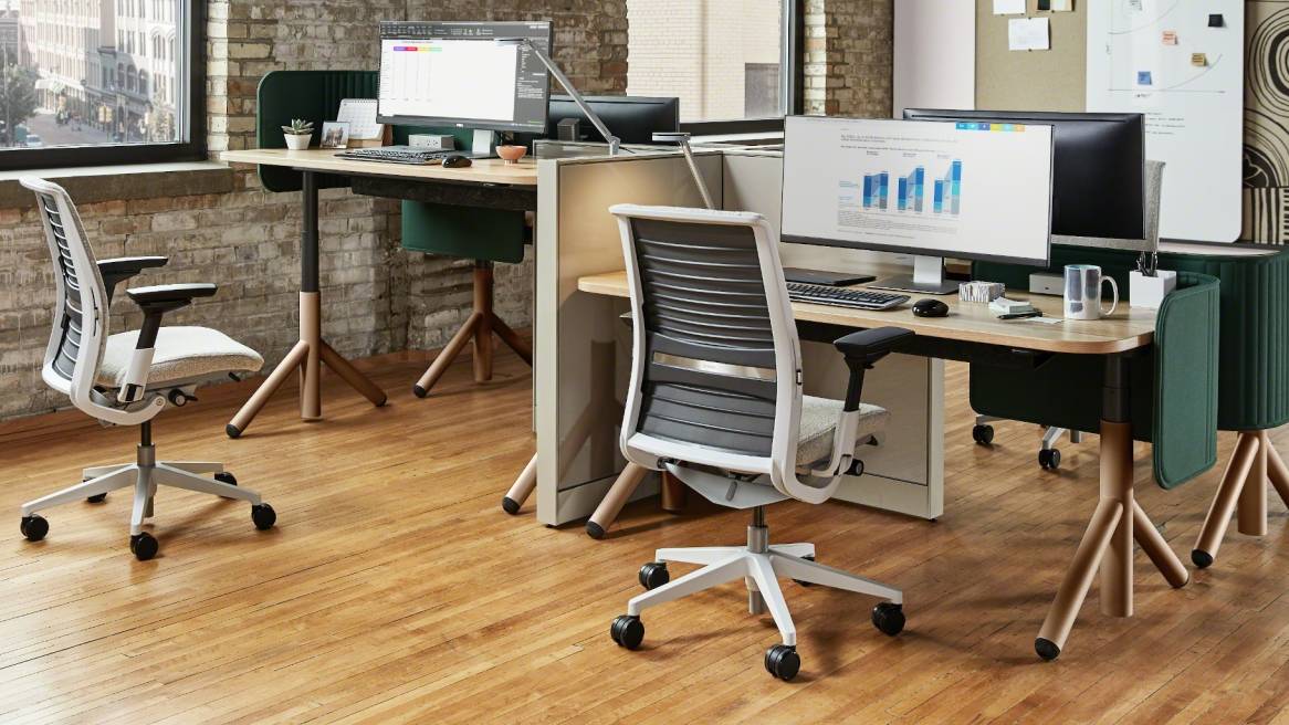 Work area with a wooden desk, a big monitor on it and a Think chair